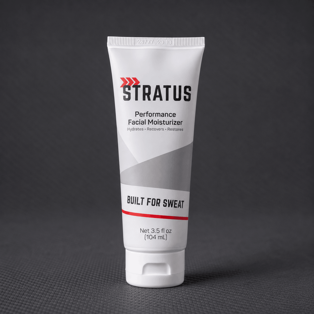 A white squeeze tube of Stratus Performance Facial Moisturizer, part of a post workout skincare routine, standing upright on a dark gray textured surface.