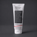 A white squeeze tube of Stratus Performance Facial Moisturizer, part of a post workout skincare routine, standing upright on a dark gray textured surface. The back view including ingredients is shown.