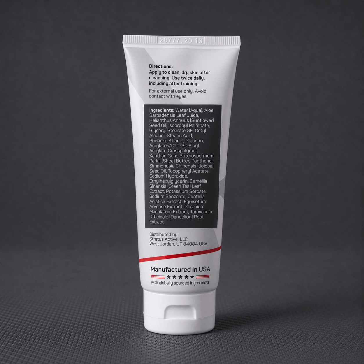 A white squeeze tube of Stratus Performance Facial Moisturizer, part of a post workout skincare routine, standing upright on a dark gray textured surface. The back view including ingredients is shown.