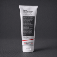 A white squeeze tube of Stratus Performance Facial Moisturizer, part of a post workout skincare routine, standing upright on a dark gray textured surface. The back view including ingredients is shown.