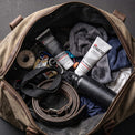 The Stratus Complete System, including a post workout cleanser and a post workout moisturizer, as part of a post exercise skincare routine. The bottles are placed in a brown gym bag alongside other exercise equipment.