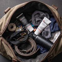 The Stratus Complete System, including a post workout cleanser and a post workout moisturizer, as part of a post exercise skincare routine. The bottles are placed in a brown gym bag alongside other exercise equipment.