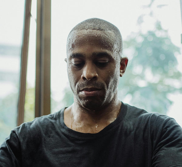 An athlete with eyes closed and sweat covering his face.